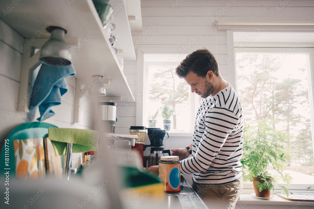Side view of man making coffee in kitchen at home Side view of man making coffee in kitchen at home