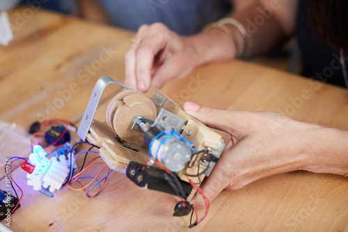 Cropped hands of mature female inventor making model at workshop
