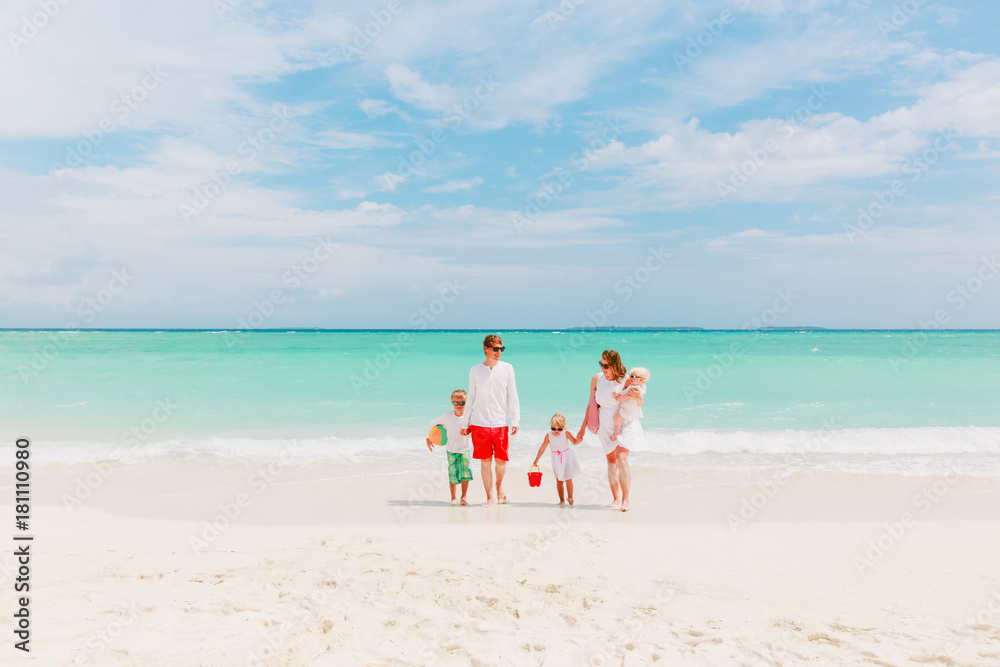 happy family with three kids walk on beach
