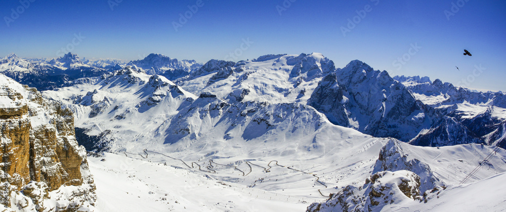 Winter mountain panorama with snow covered mountains and winding road