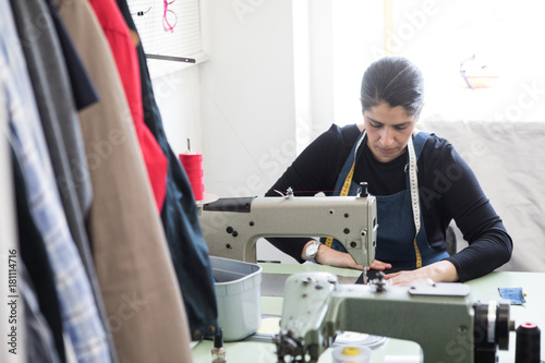 Mature female tailor using sewing machine at Laundromat photo
