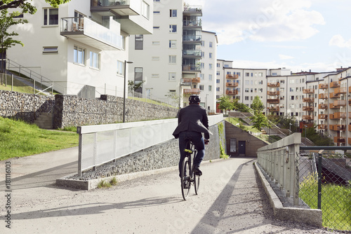 Rear view of businessman cycling on road in city