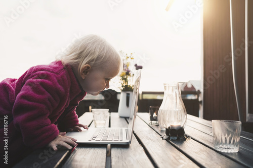 Side view of girl looking at laptop on table in holiday villa against clear sky photo