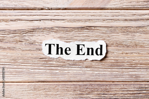 The End of the word on paper. concept. Words of The End on a wooden background photo