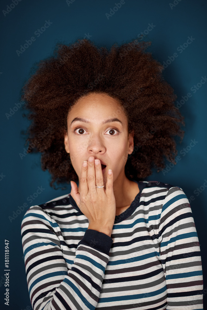 Head shot of mixed race woman with surprised face expression. Blue wall in background Head shot of mixed race woman with surprised face expression. Blue wall in background