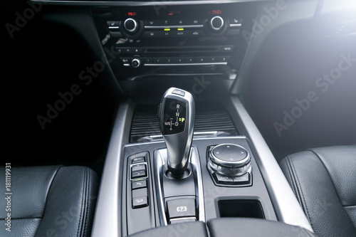 Automatic gear stick (transmission) of a modern car, multimedia and navigation control buttons. Car interior details. Transmission shift. Soft lighting