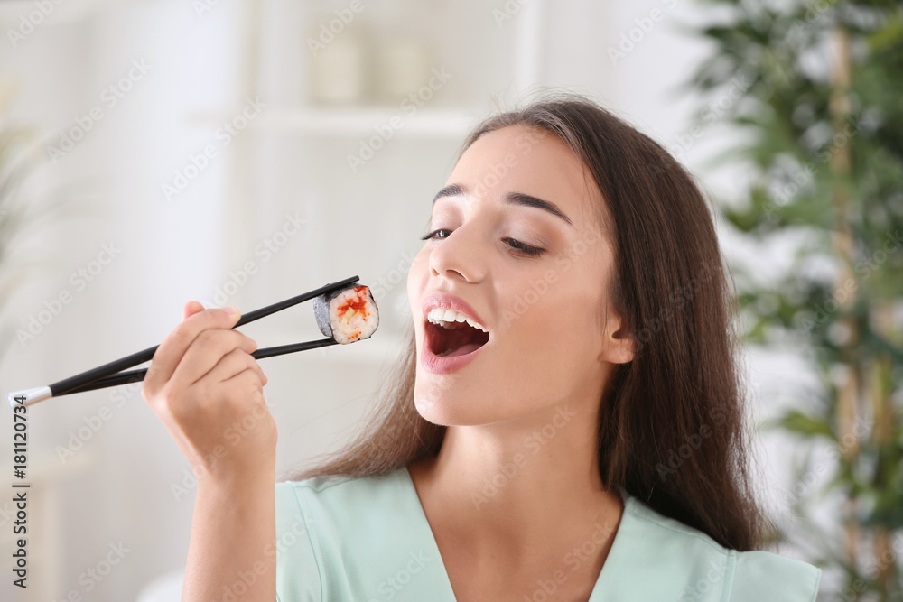 Beautiful young woman eating sushi roll at home Beautiful young woman eating sushi roll at home