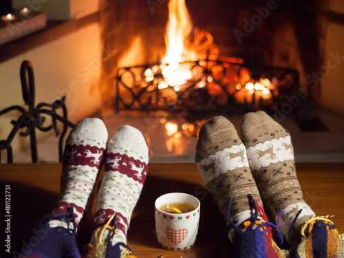 Man and woman in warm socks near fireplace. Happy couple.	