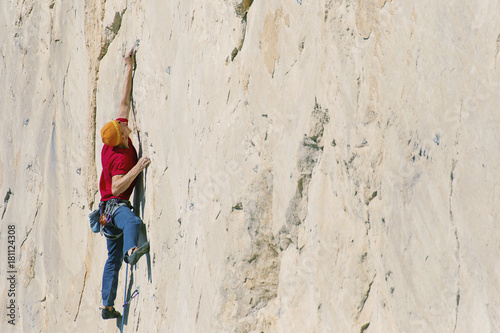 A climber man climbs to the top of a cliff.