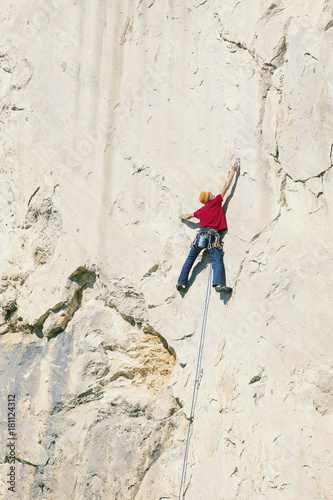 Fototapeta Naklejka Na Ścianę i Meble -  A climber man climbs to the top of a cliff.