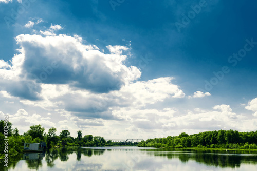Beautiful summer rural landscape with river and clouds on the blue sky. Russia. Ural. Village Sloboda