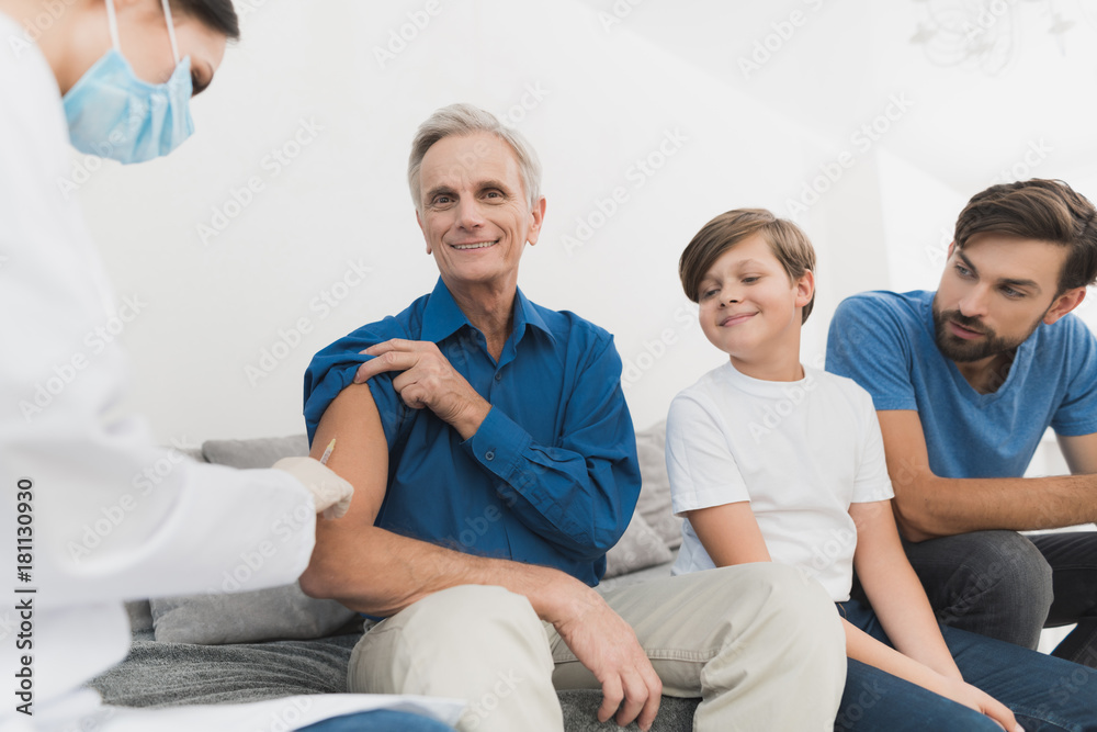 Obraz premium A nurse makes an insulin shot of an old man. A nurse is sitting in a mask and gloves on the couch.