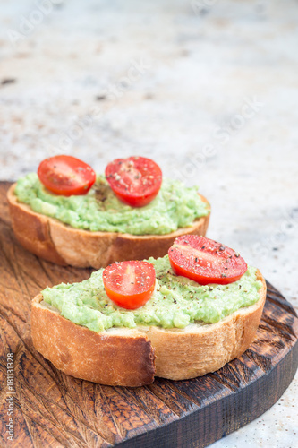 Open sandwiches with mashed avocado and cherry tomatoes, vertical, copy space