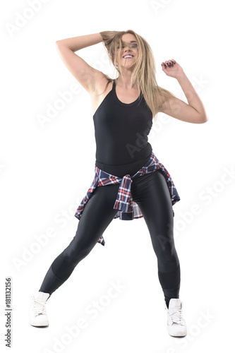Smiling relaxed woman dancer with hand in hair moving and dancing looking at camera. Full body length portrait isolated on white studio background. 
