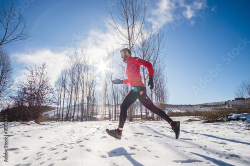 Man running on the snow in a forest photo