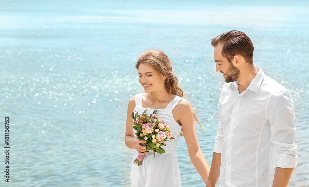 Happy newlywed couple walking on seashore