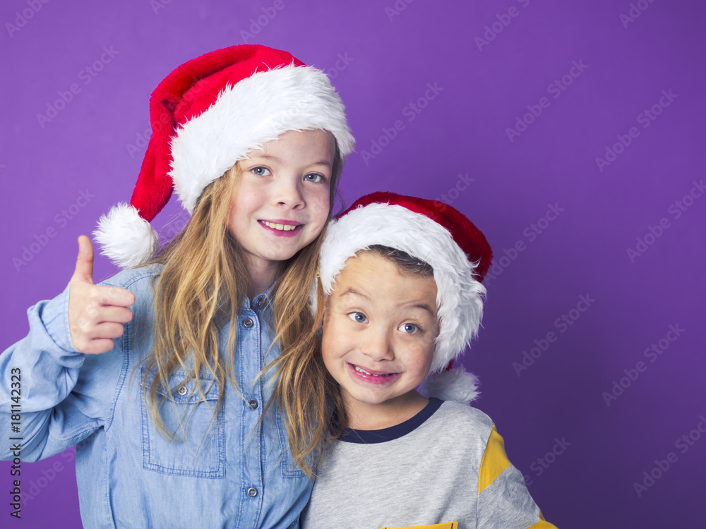 brother and sister with christmas decoration on head in front of violet background brother and sister with christmas decoration on head in front of violet background