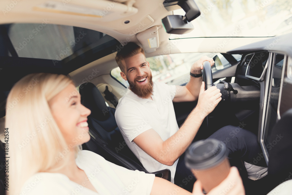 A young couple is sitting in the cabin of a comfortable modern electric car. A young couple is sitting in the cabin of a comfortable modern electric car.