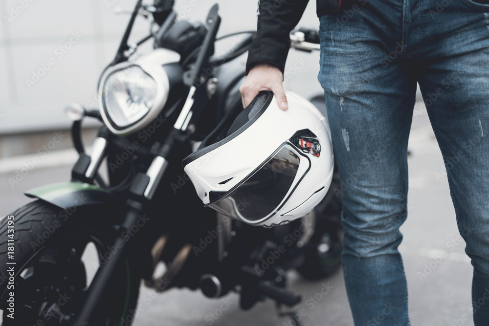 Naklejka premium A young guy stands near an electric motorcycle.