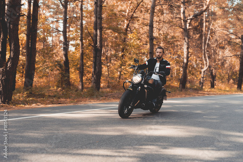 A young guy with a beard is riding on a forest road on an electric motorcycle.