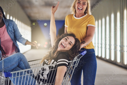 Girlfriends playing with a shopping cart together at night