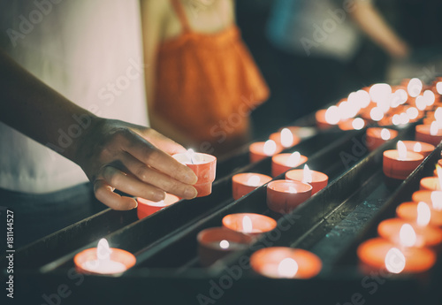 Woman puts a candle on altar in church.