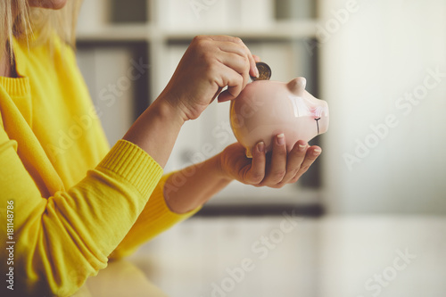 Woman inserts a coin into a piggy bank
