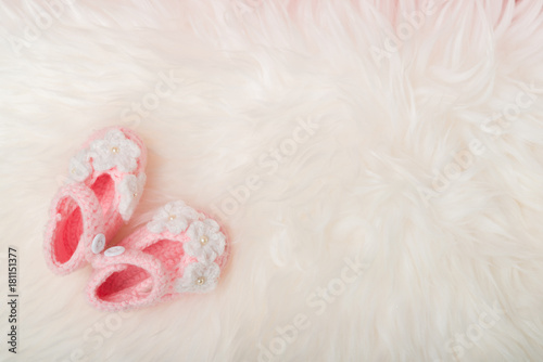 Close up Baby girl knitted shoes on white blanket background.Happy new year greeting card with copy-space. New born celebration holiday concept.