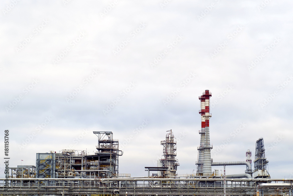 general view of a chemical or oil refinery with a multitude of pipelines, factory pipes and distillation columns under a cloudy sky