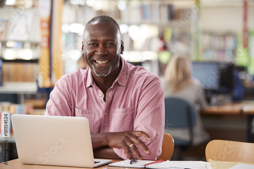 Portrait Of Mature Male Student Using Laptop In Library photo