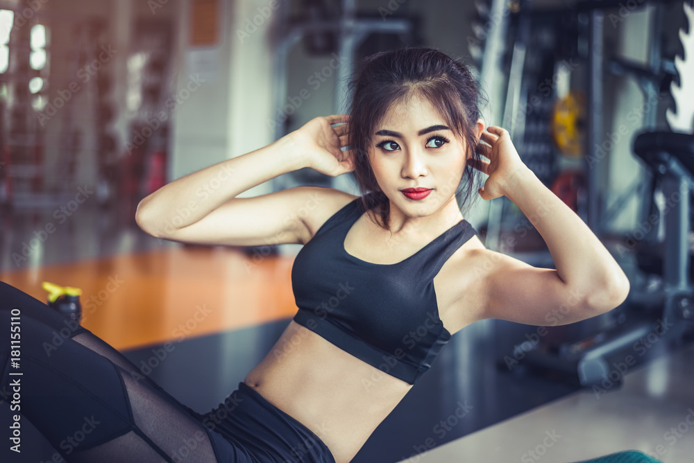 Side view of Asian fitness girl doing crunch twist at fitness gym. Sports and workout concept. Fitness gym and beauty theme.