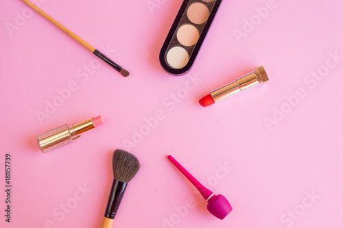 Lipstick, eye shadow, eyeliner cosmetics for girl on pink table background 