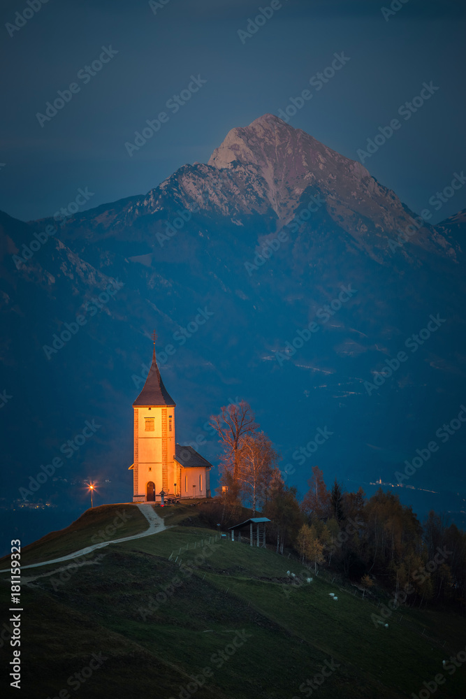 Jamnik, Slovenia - Beautiful illuminated St. Primoz hilltop church with Julian Alps at background at blue hour