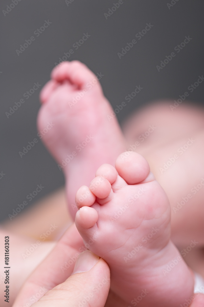 Mother giving baby foot massage against colic Mother giving baby foot massage against colic