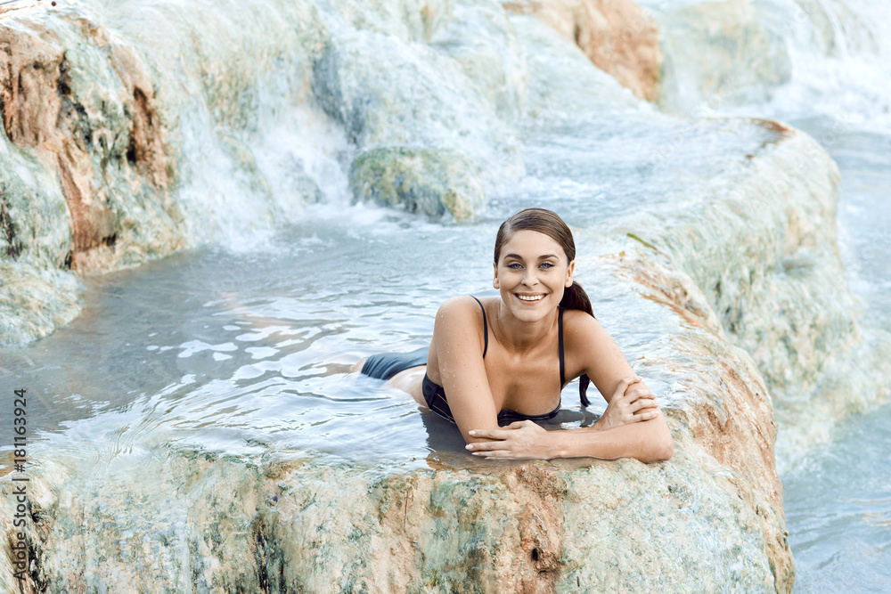 Pretty young brunette woman taking a bath in the natural thermal waters of spa, Saturnia Italy