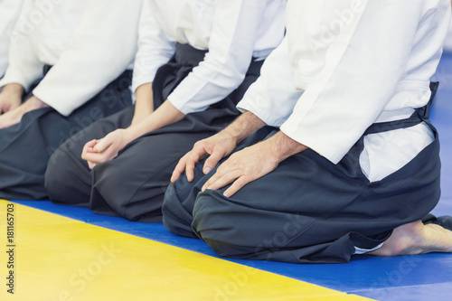 People in kimono and hakama sitting in a line on tatami. Selective focus