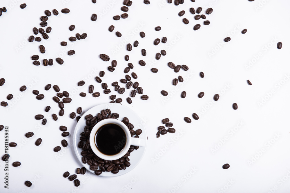 Obraz premium Morning coffee, the concept of still life. An inscription made of coffee beans on a white background next to a cup of coffee. Heart made of coffee beans and inscription love
