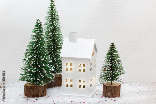 Minimalistic bright christmas composition with decorative  fir tree,wooden sledge , white metal lantern house snow and sparkling red stars.