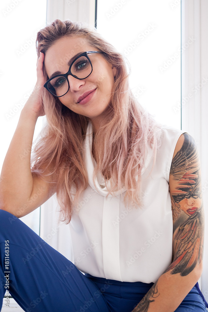 Sexy blonde business woman with a tattoo on her hand next to a window in an  office interior Stock Photo | Adobe Stock