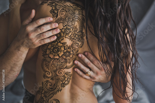 A beautiful pattern made with henna on the bare back of the girl 220.