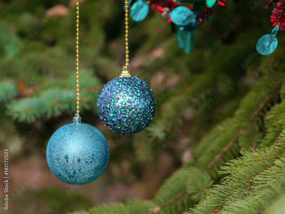 New Year balls hang on a gold chain. Fluffy green spruce.