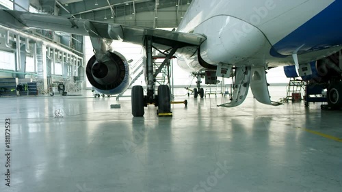 Airplane in hangar, rear view of aircraft and light from windows. Business jet airplane is in hangar. The airplane in the hangar, behind the whole plane and the gangway photo