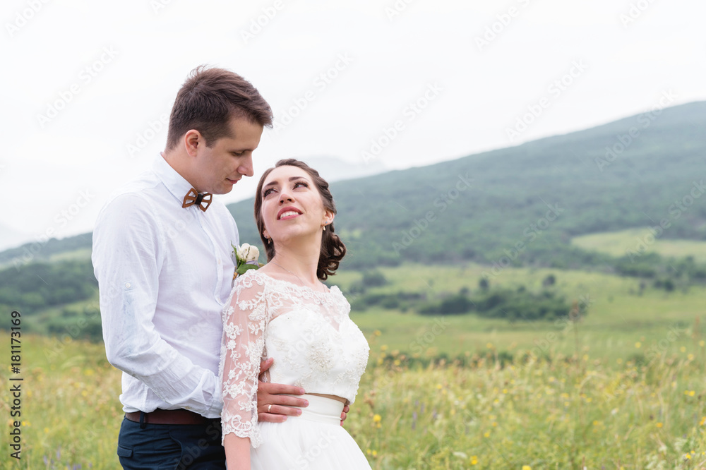 a couple of newlyweds standing in an arms embrace in nature