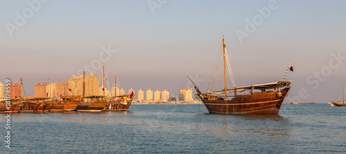 Traditional wooden boats dhow in Katara beach in Doha,Qatar Daylight view with Qatar flag and skyline in background