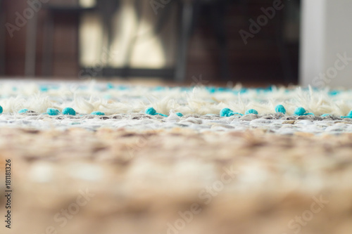 colorful turquoise handmade woven rug close up consisting of various textures with wooden floor