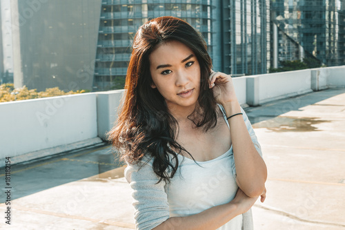 Young asian woman posing on rooftop level in cityscape wearing casual clothes	