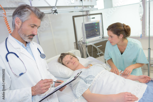 mature male doctor visiting female patient with nurse