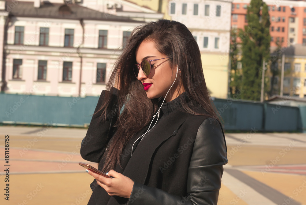 Fototapeta premium Closeup portrait of smiling brunette woman watching video on mobile telephone, standing at the street