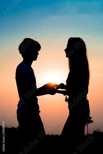 silhouette of a couple lovers standing holding hand at the sunset time and they gaze into each other’s eyes. Have a beauty pink and blue sky. © Anek