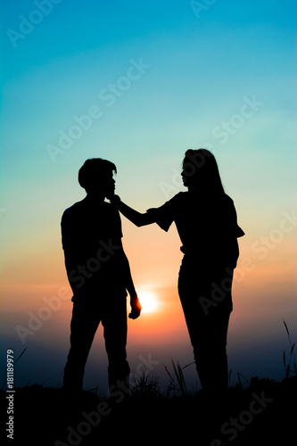 silhouette of romantic couple at the sunset time on meadow. Have a beauty pink and blue sky.